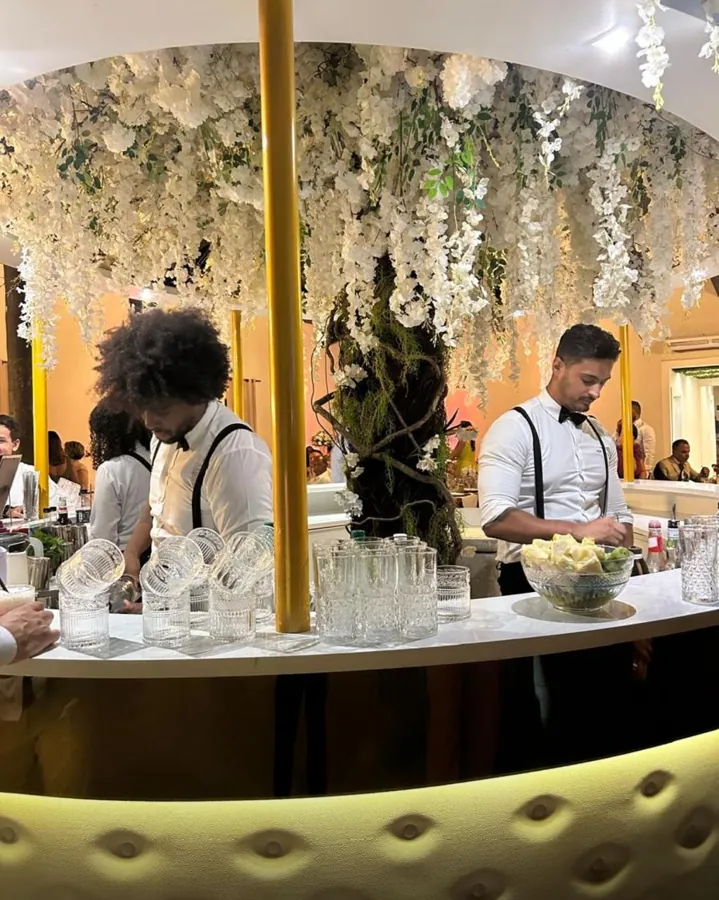 Bartenders servindo em bar redondo decorado com flores